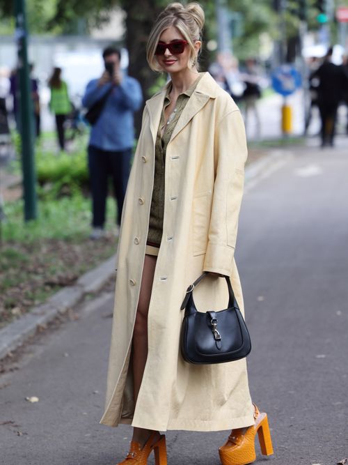 Xenia Adonts wears green polo neck top, butter yellow leather coat, black Gucci bag, orange platform Gucci heels, outside Gucci, during the Milan Fashion Week Spring/Summer 2025 on September 20, 2024 in Milan, Italy.