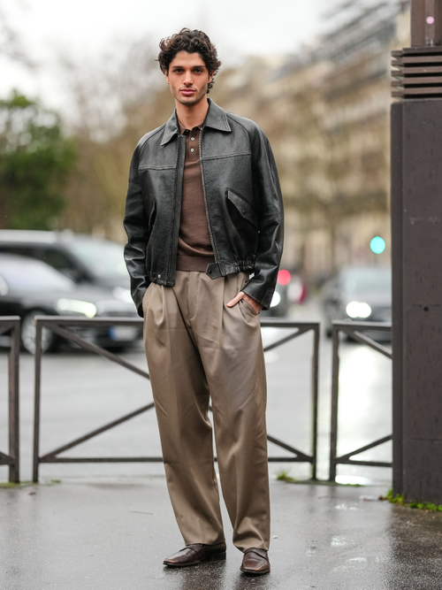 A guest wears deep dark brown sweater, shiny black leather jacket, dark brown relaxed trouser pants, shiny dark brown loafer moccasin leather shoes, outside Hermes, during the Paris Fashion week Men’s Fall/Winter 2025-2026 on January 25, 2025 in Paris, France.