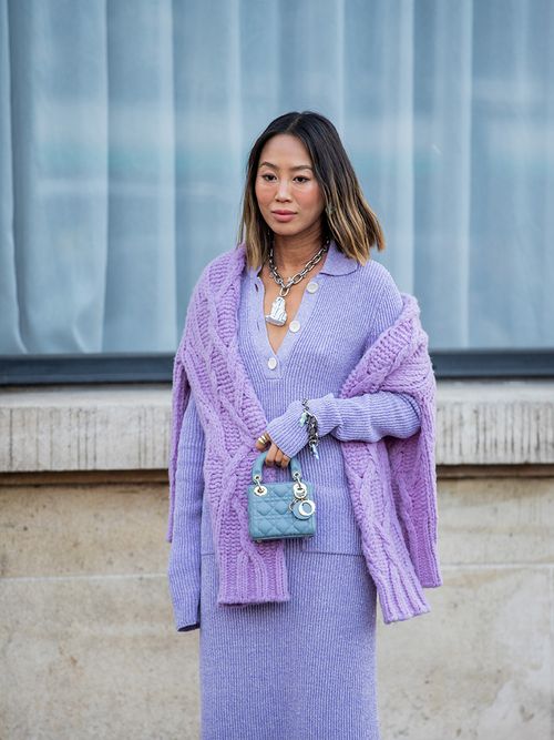 Streetstyle mit einem lila Strickkleid und einem lila Pullover um die Schultern.