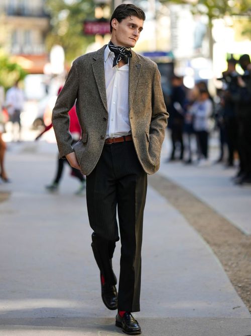 Street Style Look von der Paris Fashion Week. Ein Mann trägt ein braunes Sakko aus Wolle mit schwarzer Hose und weißem Hemd, dazu ein Halstuch.