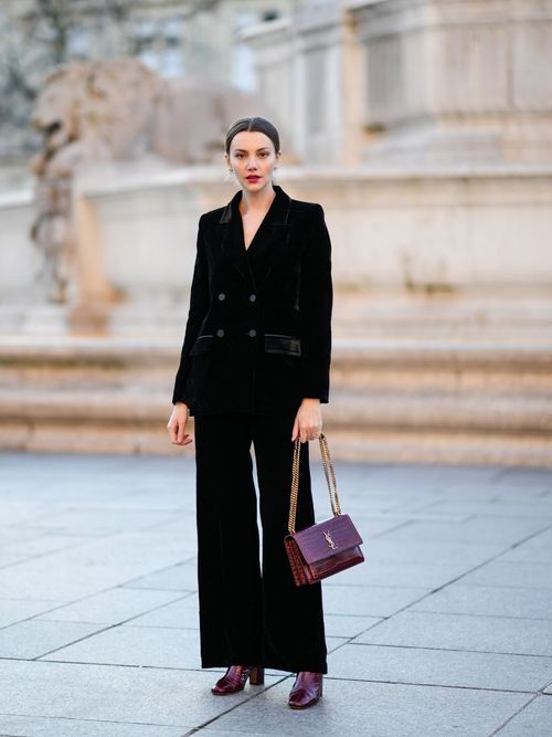 Olesya Senchenko trägt einen Hosenanzug aus Samt in Schwarz mit einer Bordeauxfarbenen Tasche in Paris