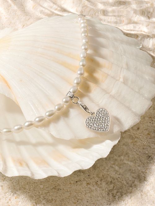 Perlenkette mit Herz auf einer Muschel.