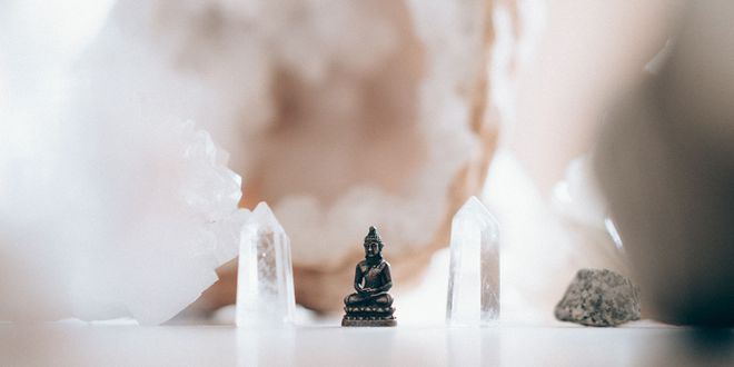 Eine kleine Buddhafigur, die zwischen zwei Bergkristallen steht.