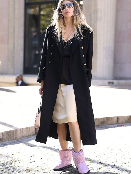 Veronika Heilbrunner mit einem beigen Satinrock zu einem schwarzen Wollmantel und rosa Daunenschuhen.