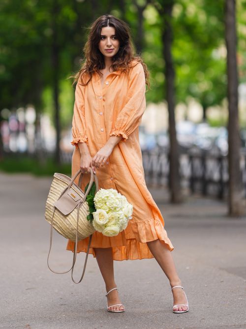 Ketevan Giorgadze trägt ein orangefarbenes Leinenkleid mit einem Bast-Shopper in Paris.