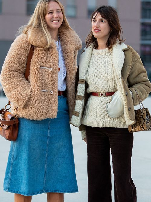 Streetstyle mit einer Frau im Jeansrock und Teddyjacke und eine andere im weißen Strickpullover und einer Shearlingjacke.