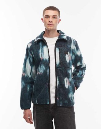 Rains 19000 Yermo - Pile verde e blu con stampa sfocata e chiusura con zip