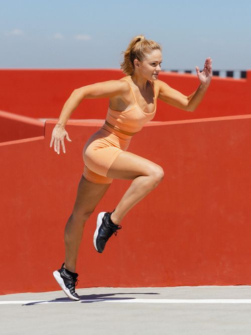 Junge Sportlerin im sommerlichen Sportoutfit beim Sprinten