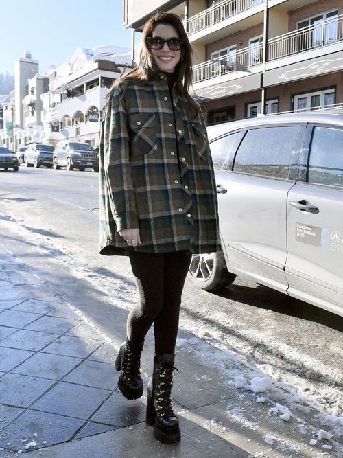 Anne Hathaway wears a plaid shacket with leggings and black hiking boots