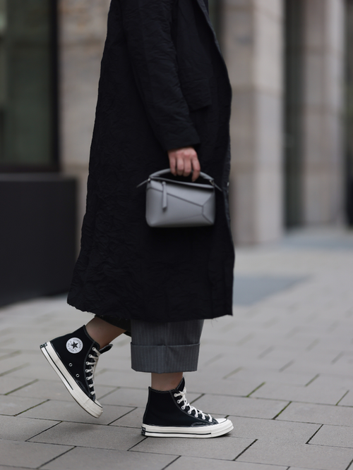 A guest wears all-black and a pair of black and white Converse sneakers