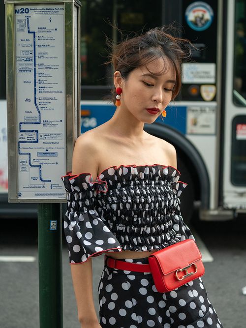 Frau mit schulterfreiem Polka Dot Top und einer roten Gürteltasche in New York.