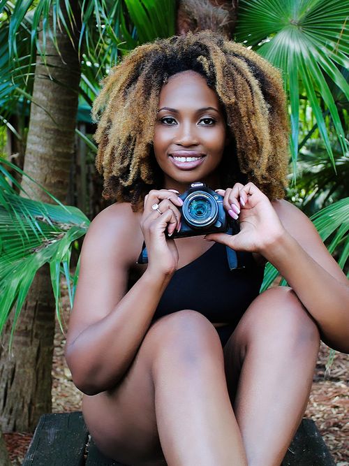 Lachende curvy Frau im Badeanzug mit Kamera in der Hand.