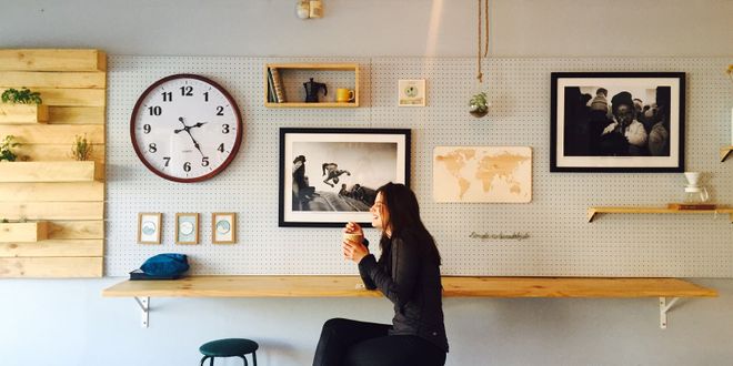 Frau sitzt an Theke, lacht und trinkt Kaffee