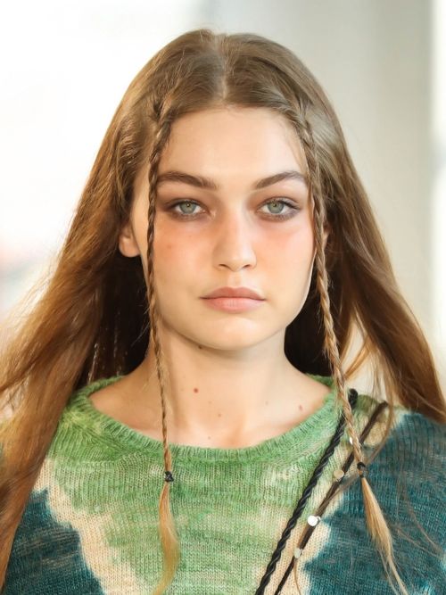 Gigi Hadid mit einem grünen Batiktop und zwei kleinen geflochtenen Zöpfen.