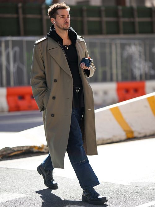 Ein Gast auf der New York Fashion Week trägt einen grauen Mantel, darunter einen schwarzen Hoodie mit Jeans und Capy.