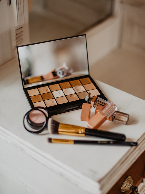 Gebrauchte und offene Make-up Produkte die auf einem weißen Untergrund liegen.