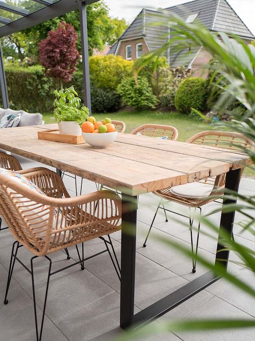 Terrasse mit einem Holztisch und Stühlen auf Rattan.