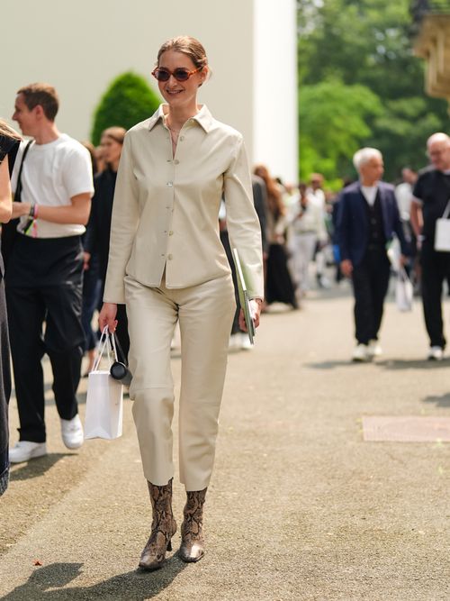 Street Style Look von der Paris Fashion Week, wo ein Gast eine weiße Bluse, weiße Denim und Stiefeletten im Animalprint trägt.