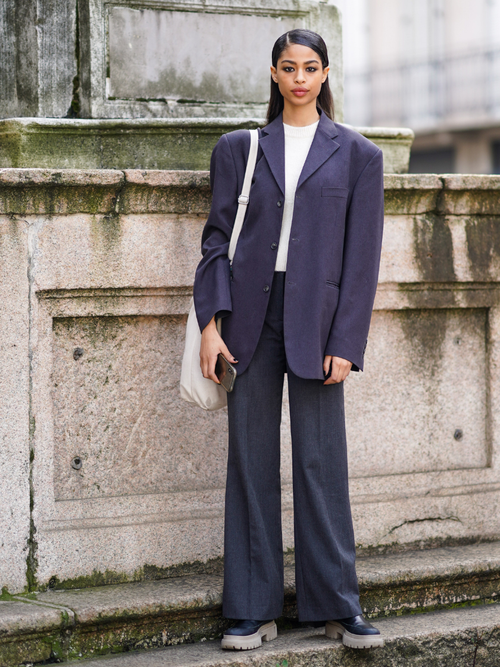 Ein Model trägt einen graublauen Hosenanzug in Oversize mit einem weißen T-Shirt und Tasche auf der Milan Fashion Week.