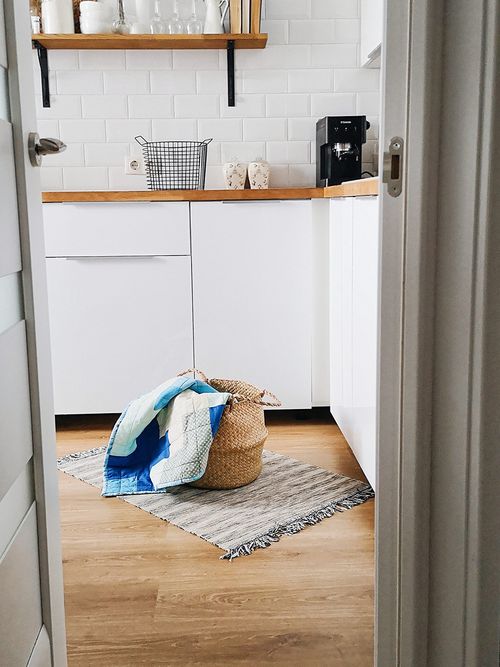 Ausschnitt einer Küche mit weißen Möbeln und einem Wäschekorb, der auf dem Boden steht.