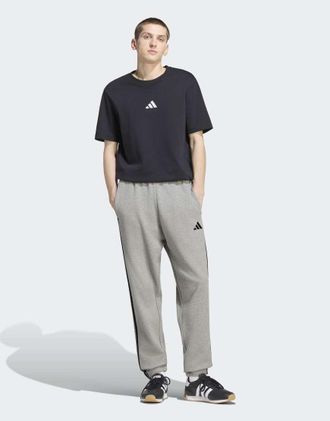 adidas adidas Performance - Essentials - Pantaloni affusolati in spugna grigio m&eacute;lange medio con 3 strisce e polsini elasticizzati bianchi
