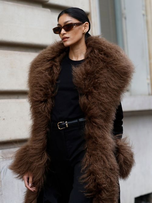 Pritika Swarup wears black top, black trousers, black coat with brown fur details, on the streets of Paris, during Haute Couture Spring-Summer 2025 as part of Paris Fashion Week on January 28, 2025 in Paris, France.