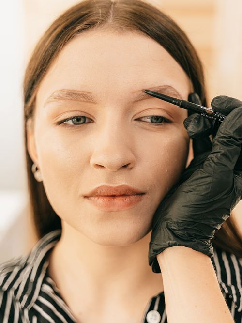 Frau lässt sich die Augenbrauen nachzeichnen.