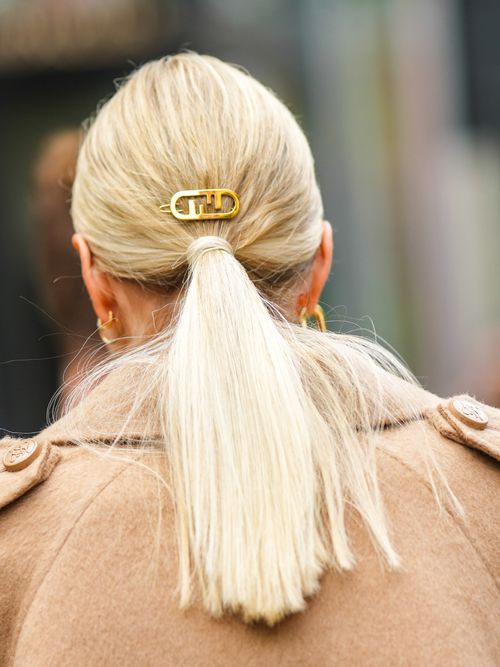 Leonie Hanne trägt einen beigen Mantel mit Zopf und goldener Haarklammer.