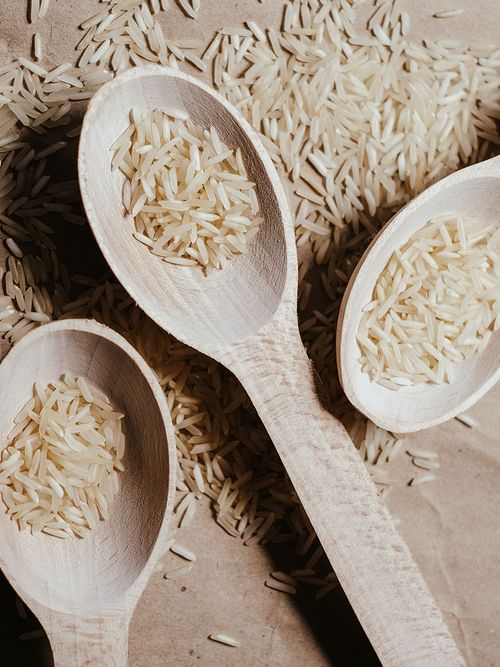 Holzlöffel mit rohem Reis auf Backpapier.