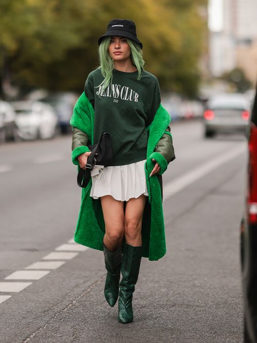 Streetstyle mit einem grünen Lammfellmantel zu einem grünen Sweatshirt, einen weißen Tennisrock und grüne Boots.