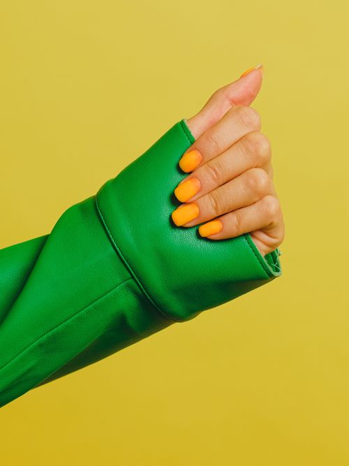 Ein still life Bild mit einer Hand mit grünem Hemd und gelben Fingernägel.