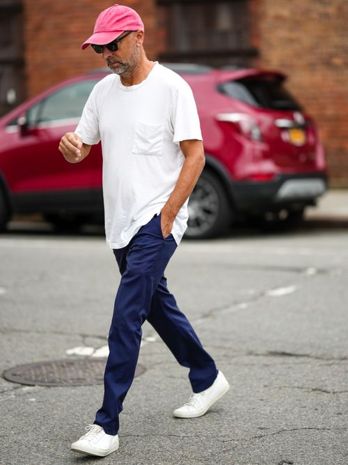Street Style Look von der New York Fashion Week, wo ein Gast ein weißes T-Shirt, pinker Cap und Bluejeans mit weißen Sneakers trägt.