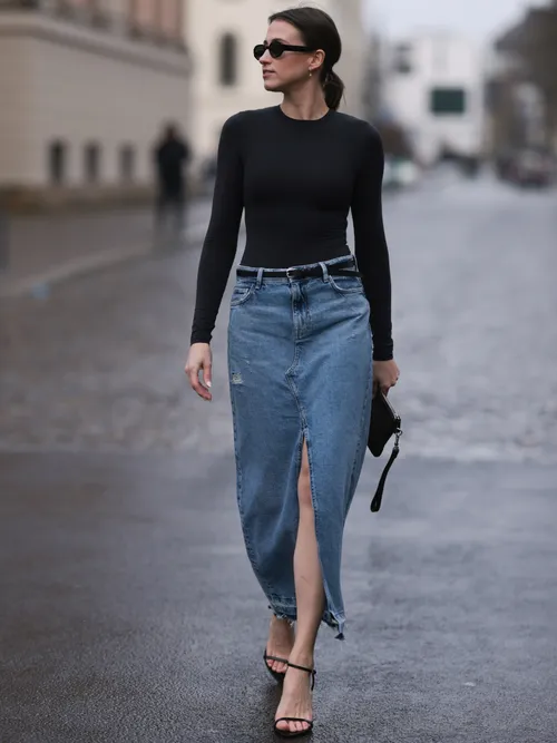 Marie Danker trägt einen langen Jeansrock mit Schlitz, mit einem enganliegenden Langarmshirt und schwarzen Sandaletten in Berlin.