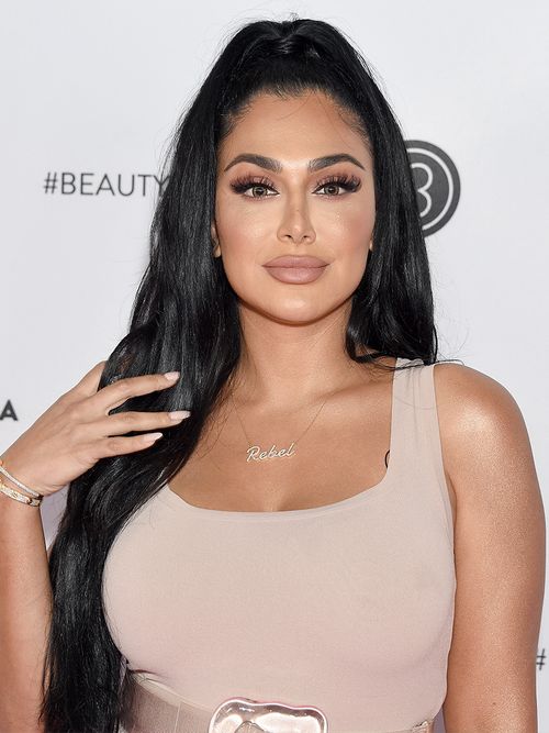 Huda Kattan in einem beigen Top und mit langen schwarzen Haaren.