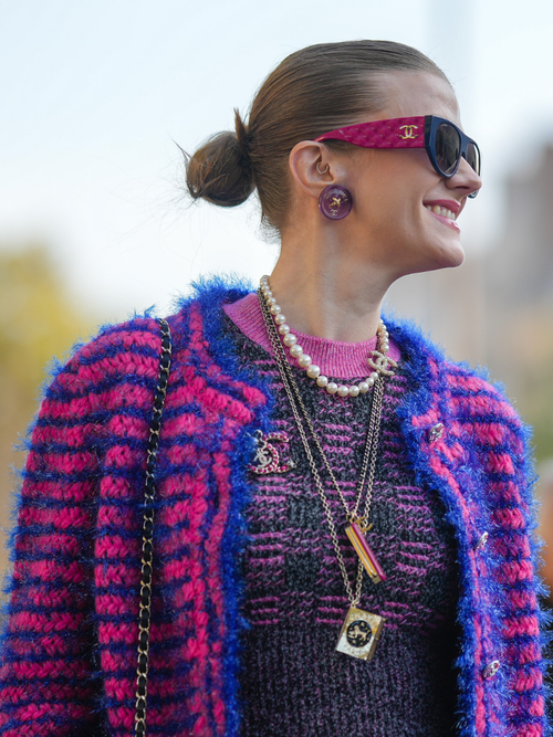 Ein Fashion Week Gast trägt verschieden große Accessoires und Schmuck mit einer Boucléjacke von Chanel