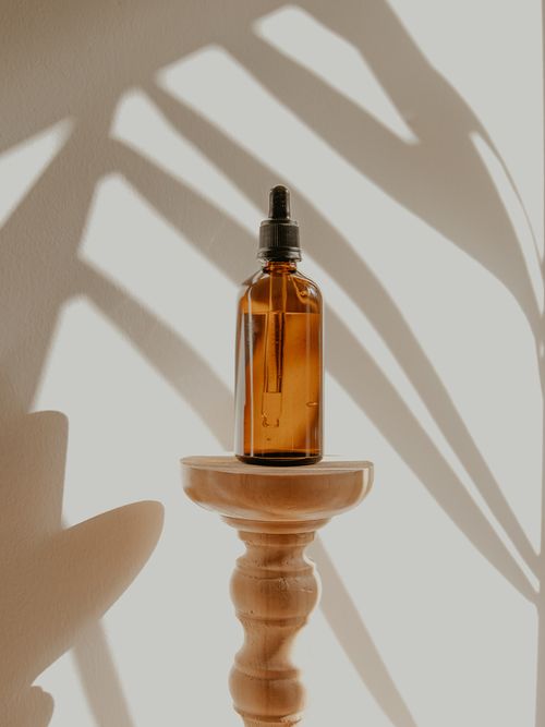 Ein braunes Glasfläschchen das auf einem hölzernen Tischchen steht.