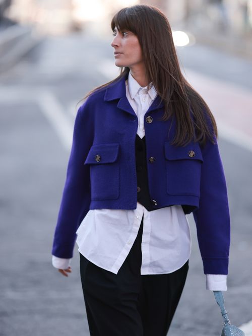 Street Style Look von der New York Fashion Week, wo ein Gast eine cropped Jacke trägt. Darunter eine weiße Bluse mit Anzugweste und schwarzer Hose.