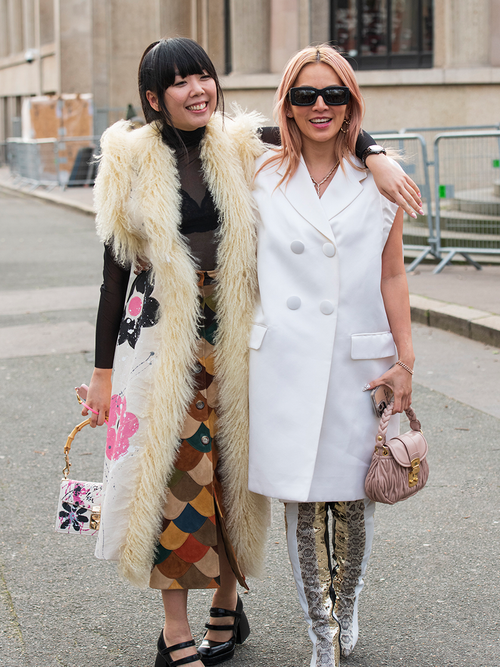 Susie Bubble in einer Fellweste und einer Frau in einer weißen Blazerweste.