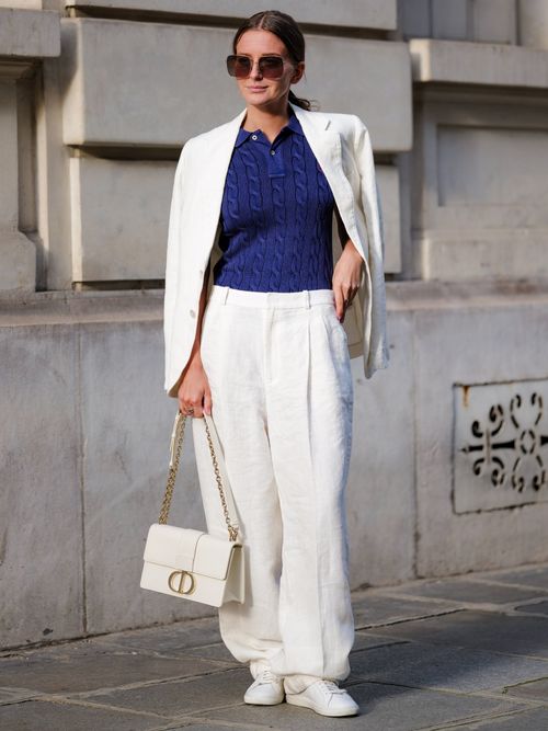 Diane Batoukina trägt einen weißen Leinen Anzug mit blauem Strickpullover und weißer Ledertasche in Paris.