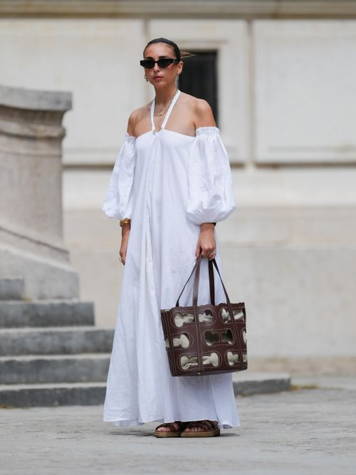 Gabriella Berdugo trägt ein weißes Kleid aus Leinen mit Carmen-Ausschnitt und Neckholder Details in Paris.