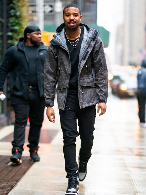 Michael B. Jordan in einem grauen Anorak und einer schwarzen Jeans.