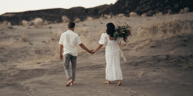 Brautpaar von hinten fotografiert, dass Händchen hält und davon spaziert.