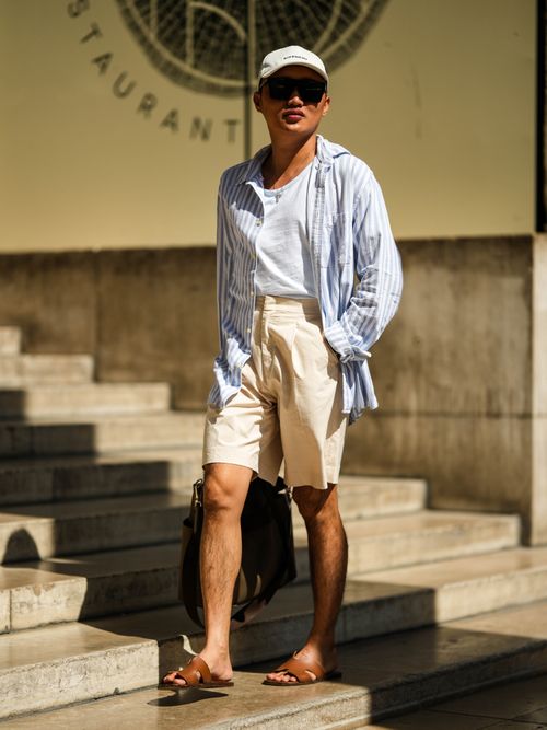 Jeck Aguilar trägt ein gestreiftes Hemd mit weißem T-Shirt und beiger Leinen-Shorts in Paris.