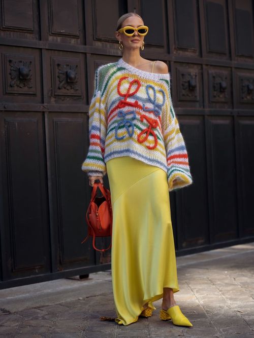 Leonie Hanne trägt einen bunten Strickpullover zum Seidenrock, mit roter Tasche und Sonnenbrille in Paris
