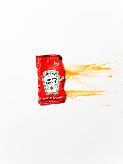 Eine zermatschte Ketchup-Packung auf weißem Hintergrund.