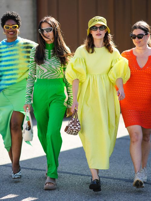 Street Style Looks von der Copenhagen Fashion Week, wo drei Frauen in bunten Outfits gehen.