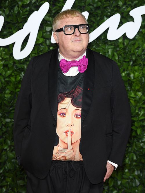 Alber Elbaz mit einem Pullover mit einem Frauengesicht und einer pinken Fliege.